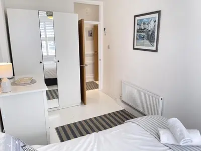 a white bedroom with a bed and a hallway at 4 Hazelbury House - a tranquil hidden gem in St Ives