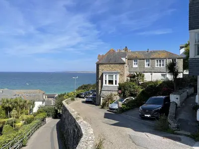a house with cars parked in front of the ocean at 4 Hazelbury House - a tranquil hidden gem in St Ives