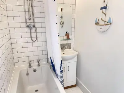 a white bathroom with a tub and a sink at 4 Hazelbury House - a tranquil hidden gem in St Ives