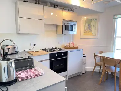 a kitchen with white cabinets and a stove top oven at 2 Upper Meadow - near to Porthmeor Beach in St Ives