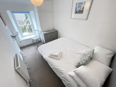 a small bedroom with a white bed and a window at 2 Upper Meadow - near to Porthmeor Beach in St Ives