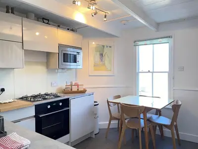 a kitchen with a table and a stove top oven at 2 Upper Meadow - near to Porthmeor Beach in St Ives
