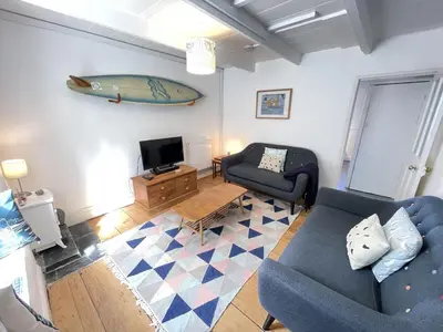 a living room with a couch and a surfboard on the wall at 2 Upper Meadow - near to Porthmeor Beach in St Ives