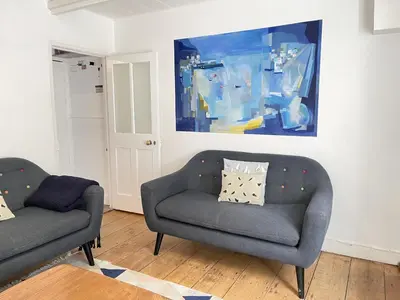a living room with two chairs and a painting on the wall at 2 Upper Meadow - near to Porthmeor Beach in St Ives