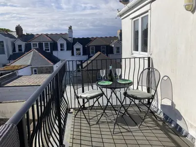 a balcony with two chairs and a table with wine glasses at Flat 4, 10 Porthminster Terrace in St Ives