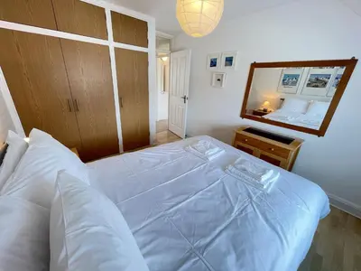 a bedroom with a large white bed and a mirror at 51-52 Carrack Widden in St Ives