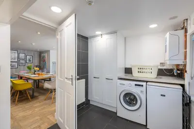 a kitchen with a washing machine and a dining room at Blue Mist House in St Ives