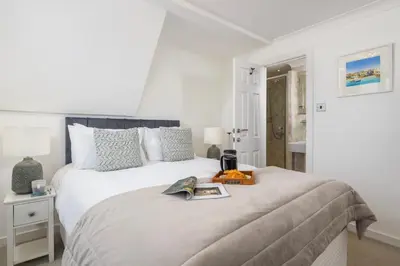 a white bedroom with a bed with a book on it at Blue Mist House in St Ives