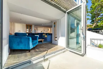 a sliding glass door opens onto a patio with a blue couch at Blue Mist House in St Ives