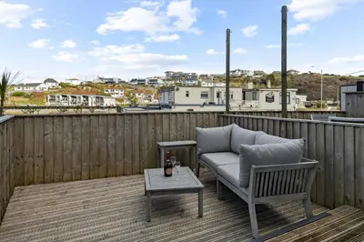 a patio with a couch and a table on a deck at 5 Mermaid Court in Newquay