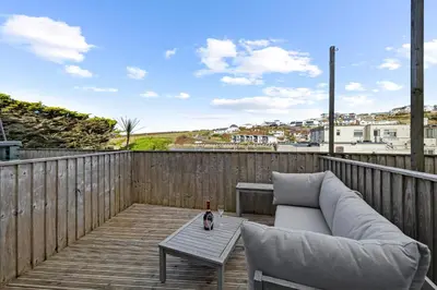 a couch and a coffee table on a wooden deck at 5 Mermaid Court in Newquay