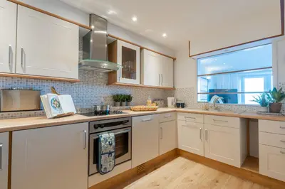 a kitchen with white cabinets and a window at Flat 17, The Stones in St Ives