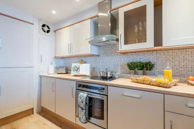 a kitchen with white cabinets and a stove top oven at Flat 17, The Stones in St Ives