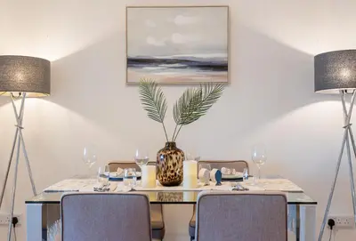 a dining room with a table with chairs and a vase at Flat 17, The Stones in St Ives