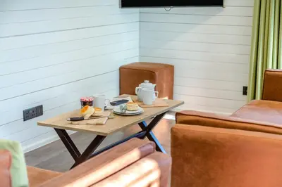 a table with two cups and plates of food on it at Lerryn Lodge, The Vale, Cornwall in Looe