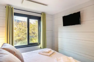 a bedroom with a bed with a tv and a window at Lerryn Lodge, The Vale, Cornwall in Looe