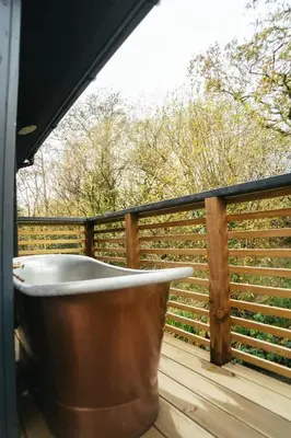 a bath tub sitting on a deck with a fence at Lerryn Lodge, The Vale, Cornwall in Looe