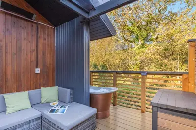 a porch with a couch and a tub on a deck at Lerryn Lodge, The Vale, Cornwall in Looe