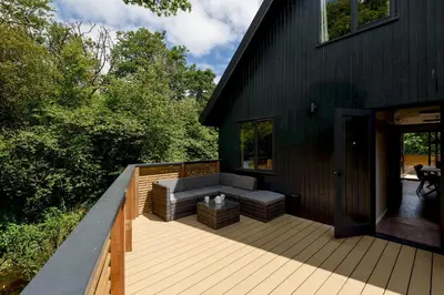 a large deck with a couch on the side of a house at Cardinham Lodge, The Vale, Cornwall in Looe