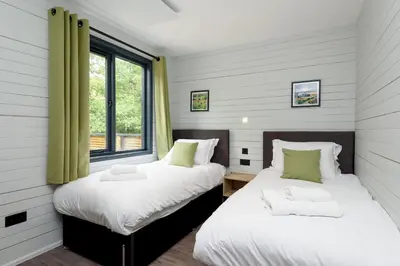 two beds in a room with two windows at Cardinham Lodge, The Vale, Cornwall in Looe