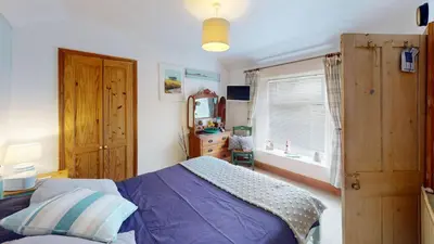 a bedroom with a bed and a dresser and a window at Hayle Saffron Cottage 2 Bedrooms in Hayle