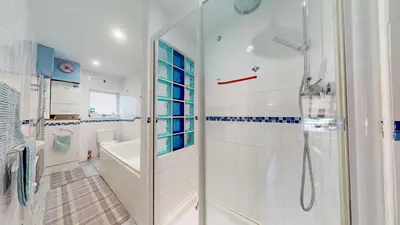 a white bathroom with a shower and a tub at Hayle Saffron Cottage 2 Bedrooms in Hayle