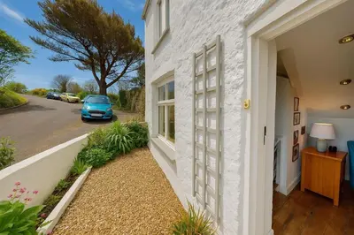 a white house with a car parked on the street at Hayle Saffron Cottage 2 Bedrooms in Hayle