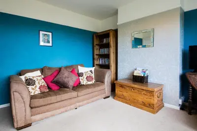 a living room with a brown couch and a blue wall at 5 Bedroom House with Sea Views in Penryn