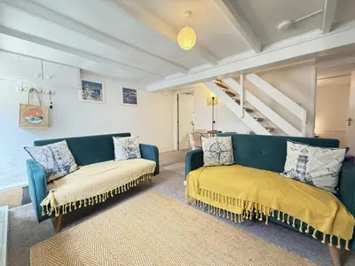 a living room with a blue couch and two chairs at Lower Deck in St Ives