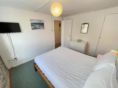 a bedroom with a white bed and a flat screen tv at Lower Deck in St Ives