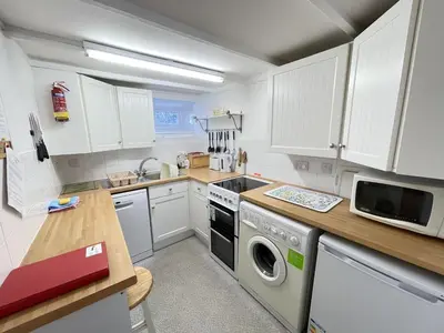 a kitchen with white cabinets and a washer and dryer at Lower Deck in St Ives