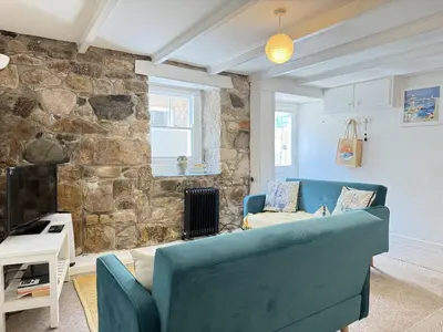 a living room with a blue couch and a stone wall at Lower Deck in St Ives
