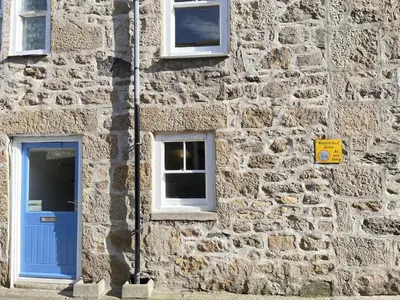 a stone building with a blue door and two windows at Lower Deck in St Ives