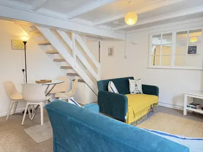 a living room with a blue couch and stairs at Lower Deck in St Ives