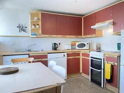 a kitchen with red cabinets and a white stove top oven at The Lookout in St Ives