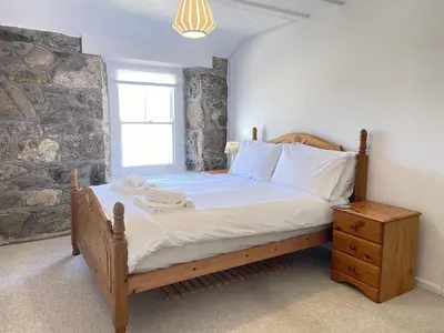 a bedroom with a bed with a stone wall at The Lookout in St Ives