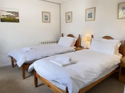two beds in a room with white sheets at The Lookout in St Ives