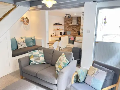 a living room with a couch and a kitchen at The Bolthole, a cosy, contemporary cottage! in St Ives