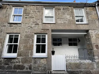 a stone house with a white door and windows at The Bolthole, a cosy, contemporary cottage! in St Ives