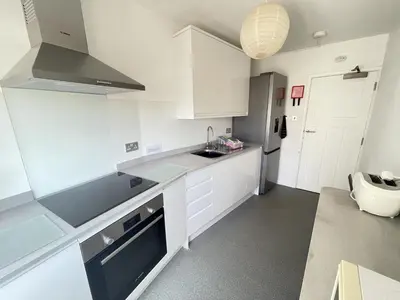 a white kitchen with a sink and a refrigerator at 3 Sunnyside - amazing harbour views in St Ives