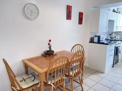 a kitchen with a table and chairs and a clock on the wall at An Marghty in St Ives