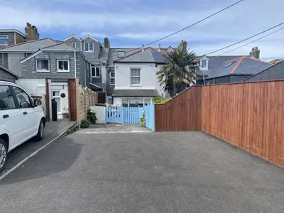 a white car parked in front of a wooden fence at An Marghty in St Ives