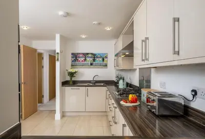 a kitchen with white cabinets and a counter top at Number 2 in Lusty Glaze, Newquay in Newquay