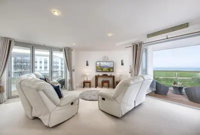 a living room with two white chairs and a table at Number 2 in Lusty Glaze, Newquay in Newquay