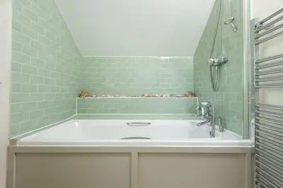 a green tiled bathroom with a tub and a sink at Sparnal Stitch and the Hideaway in Padstow