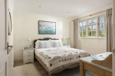a white bedroom with a bed and a window at Sparnal Stitch and the Hideaway in Padstow