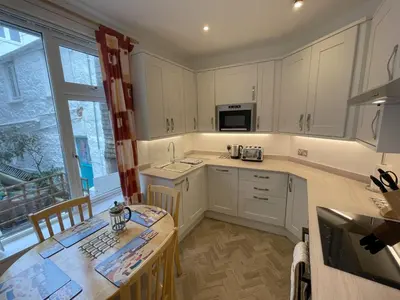 a kitchen with white cabinets and a wooden table with a table sidx sidx at Upper Seaview in St Ives