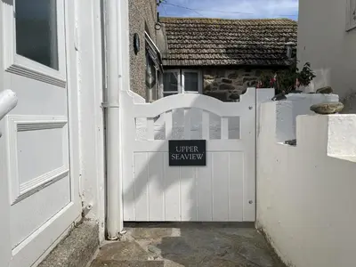 a white gate with a sign on it next to a house at Upper Seaview in St Ives