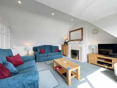 a living room with two blue couches and a table at Upper Seaview in St Ives