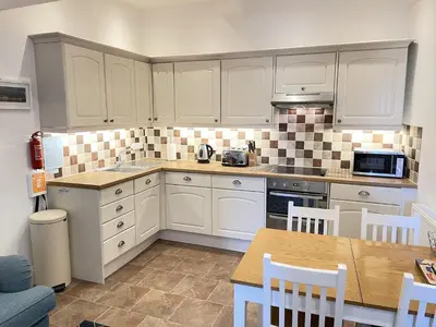 a kitchen with white cabinets and a table with chairs at Lower Seaview in St Ives
